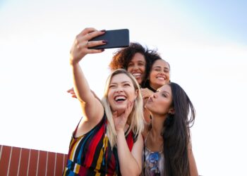 Cheerful multiethnic girlfriends taking selfie on smartphone | GRAMHIR
