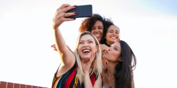 Cheerful multiethnic girlfriends taking selfie on smartphone | GRAMHIR