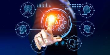 A person in a suit interacts with a virtual interface featuring an illuminated AI symbol at the center. Surrounding icons represent various elements of artificial intelligence, including brain graphics, gears, and personal finance charts, all set against a dark blue background. | GRAMHIR