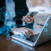 A person in a suit uses a smartphone and laptop, surrounded by digital interface elements and data graphics, symbolizing technology, proxies, and seamless data integration. | GRAMHIR
