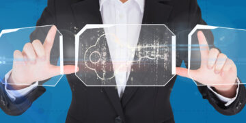 A person in a black suit and white shirt holds transparent panels showing a digital key icon and circuit patterns, symbolizing how proxies help protect intellectual property. The blue background emphasizes the themes of technology and security. | GRAMHIR