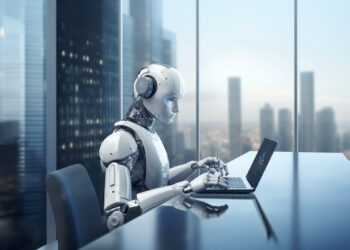 A humanoid robot, emblematic of how AI is changing the job market, sits at a desk typing on a laptop. Through large windows, a futuristic cityscape unfolds. With headphones on, the scene captures a modern technological atmosphere. | GRAMHIR