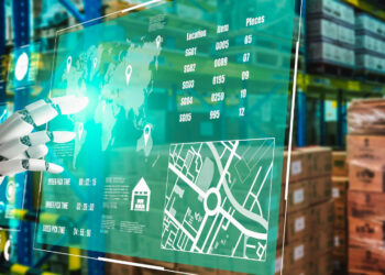 A robotic hand interacts with a transparent digital screen displaying global maps, data, and AI Supply Chain logistics in a warehouse filled with shelves of boxes and packages. | GRAMHIR