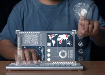 Person using virtual interface with world map, data graphics, and touch screen controls on a keyboard.