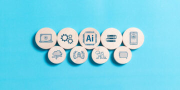 Nine wooden circles on a blue background, each with a different AI-related icon, including gears, a computer, cloud, robot arms, server, and speech bubble, representing various aspects of artificial intelligence. | GRAMHIR