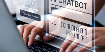 Hands typing on a laptop keyboard, with digital overlays showing "AI Chatbot," "Command Prompt," and an illustrated brain, representing artificial intelligence and chatbot technology. | GRAMHIR